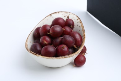 Photo of Fresh ripe red gooseberries in bowl isolated on white