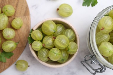 Photo of Fresh green gooseberries on white marble table, flat lay