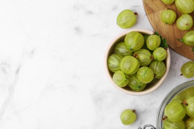 Photo of Fresh green gooseberries on white marble table, flat lay. Space for text