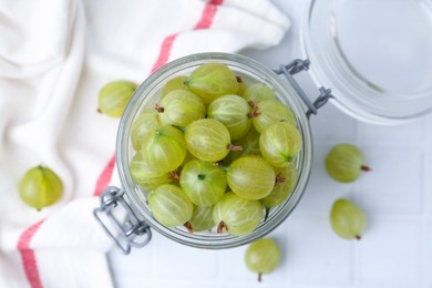 Photo of Fresh green gooseberries in jar on white table, top view