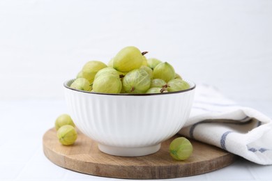 Photo of Fresh green gooseberries in bowl on white table, closeup