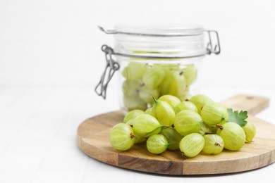 Photo of Fresh green gooseberries on white tiled table, closeup