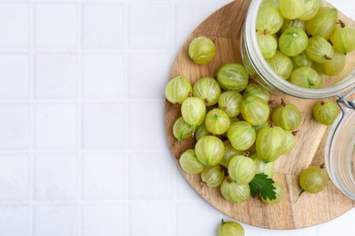 Photo of Fresh green gooseberries on white tiled table, top view. Space for text