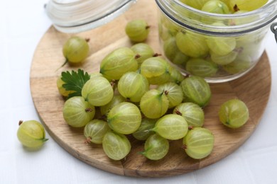 Photo of Fresh green gooseberries on white tiled table, closeup