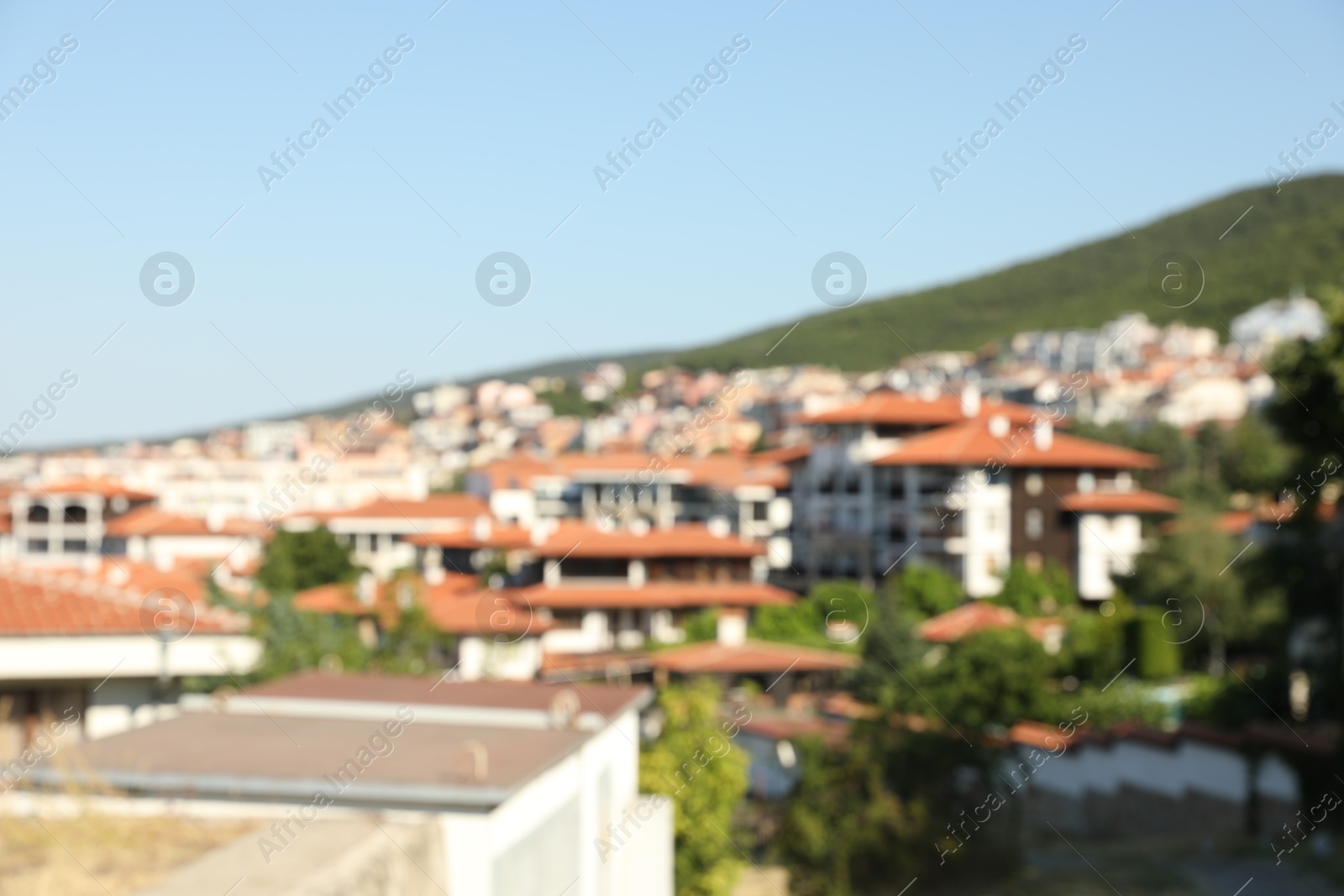 Photo of Blurred view of buildings and green mountain