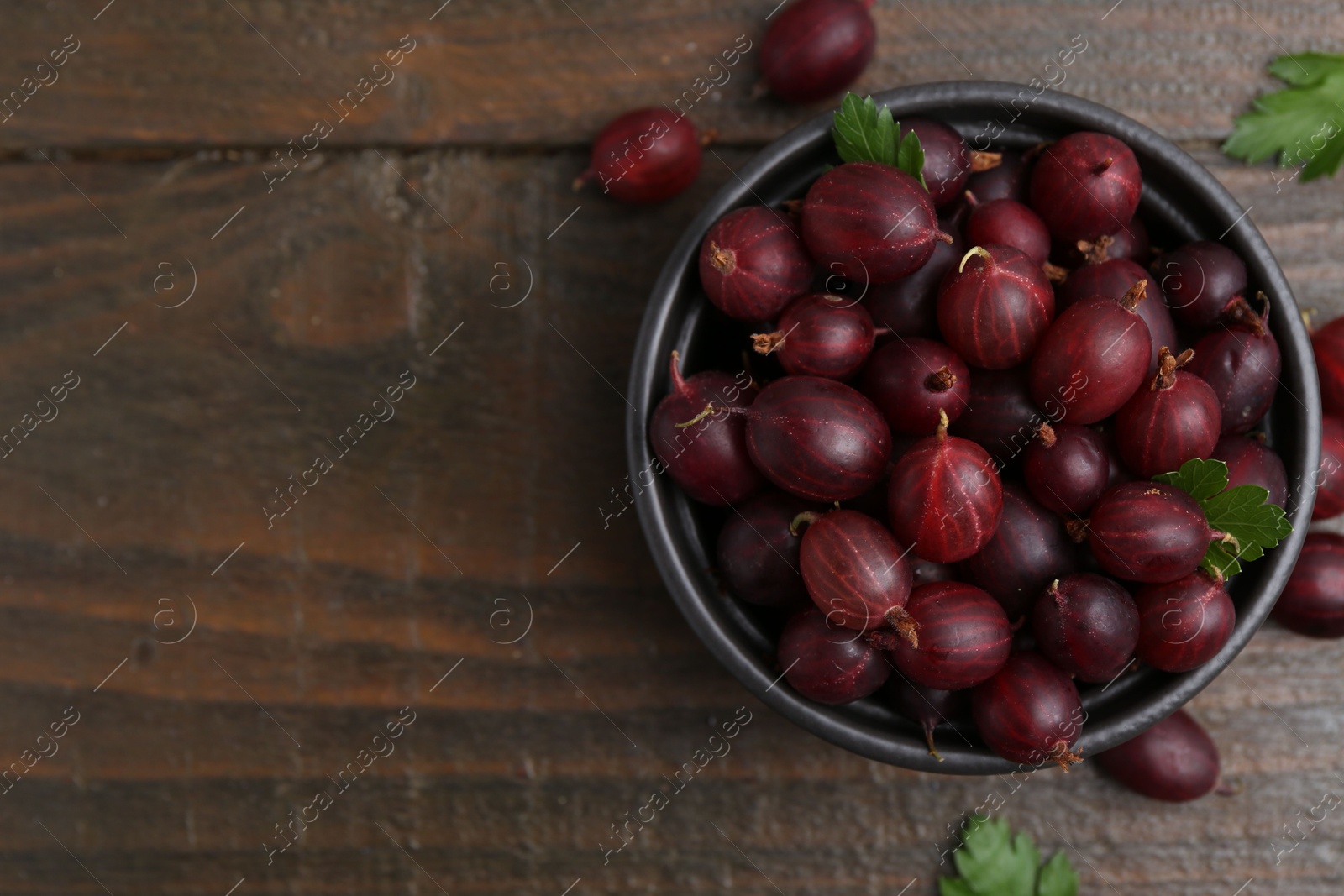 Ripe red gooseberries in bowl on wooden table, flat lay. Space for text Photo of Ripe red gooseberries in bowl on wooden table, flat lay. Space for text