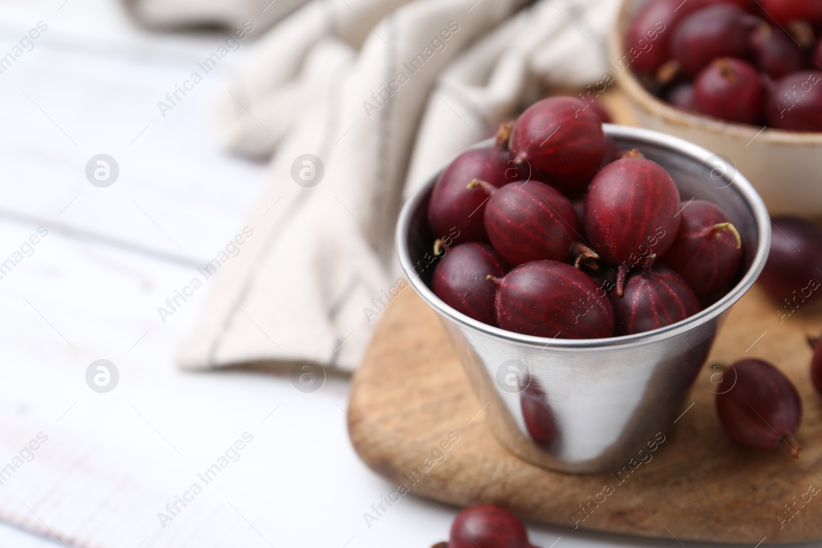Ripe red gooseberries in bowl on white wooden table, closeup. Space for text Photo of Ripe red gooseberries in bowl on white wooden table, closeup. Space for text