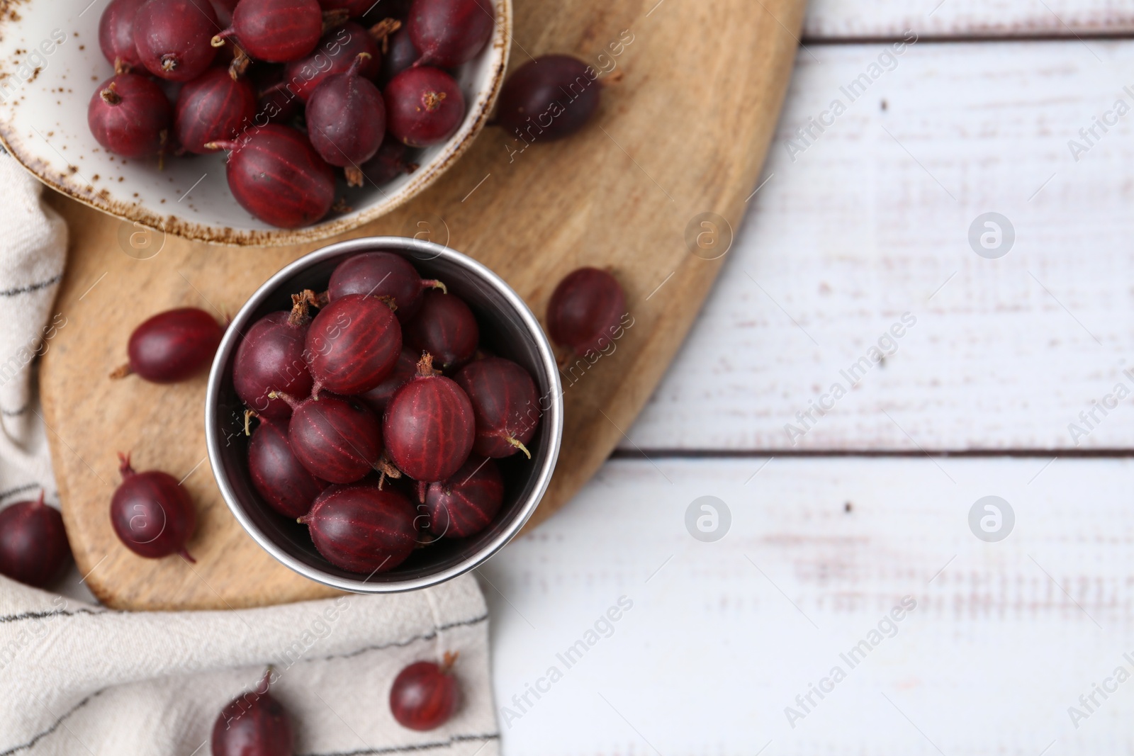 Ripe red gooseberries in bowl on white wooden table, flat lay. Space for text Photo of Ripe red gooseberries in bowl on white wooden table, flat lay. Space for text