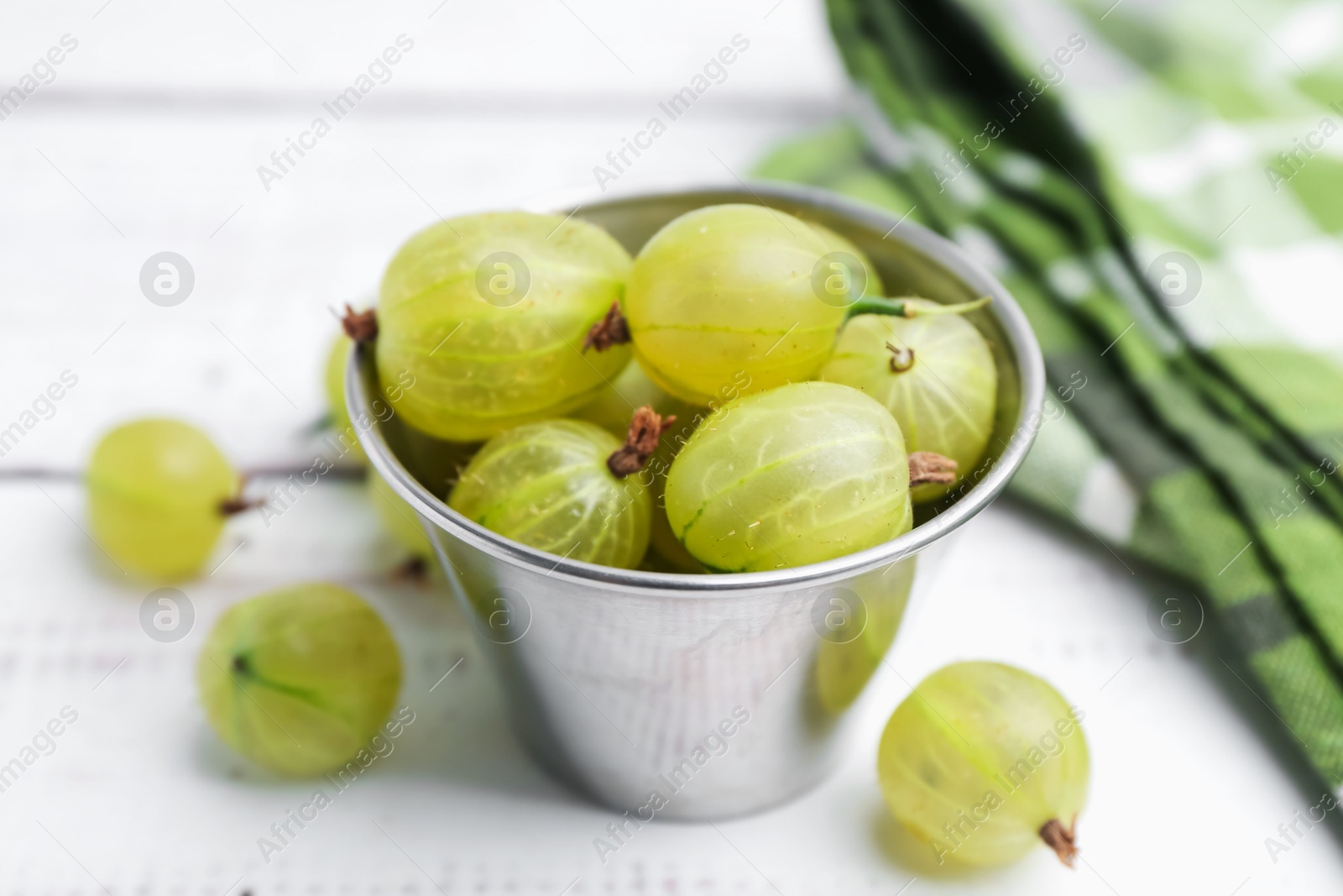 Ripe green gooseberries in bowl on white wooden table, closeup Photo of Ripe green gooseberries in bowl on white wooden table, closeup