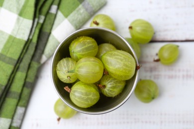 Photo of Ripe green gooseberries in bowl on white wooden table, flat lay