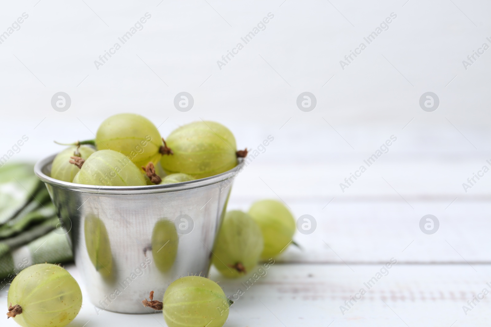 Ripe green gooseberries in bowl on white wooden table, closeup. Space for text Photo of Ripe green gooseberries in bowl on white wooden table, closeup. Space for text