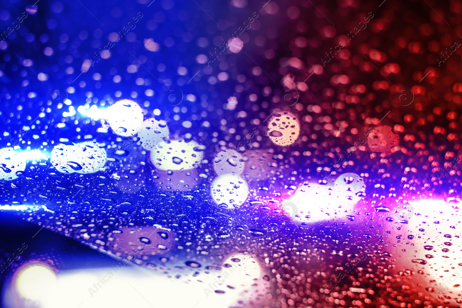 Image of Police red and blue lights at night, blurred view through wet glass. Bokeh effect