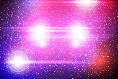 Image of Police red and blue lights, blurred view through wet glass