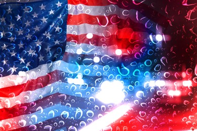Image of Police red and blue lights, flag of United States of America, view through wet glass