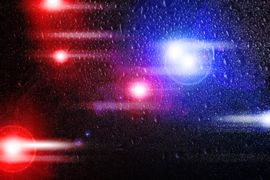 Image of Police red and blue lights, blurred view through wet glass