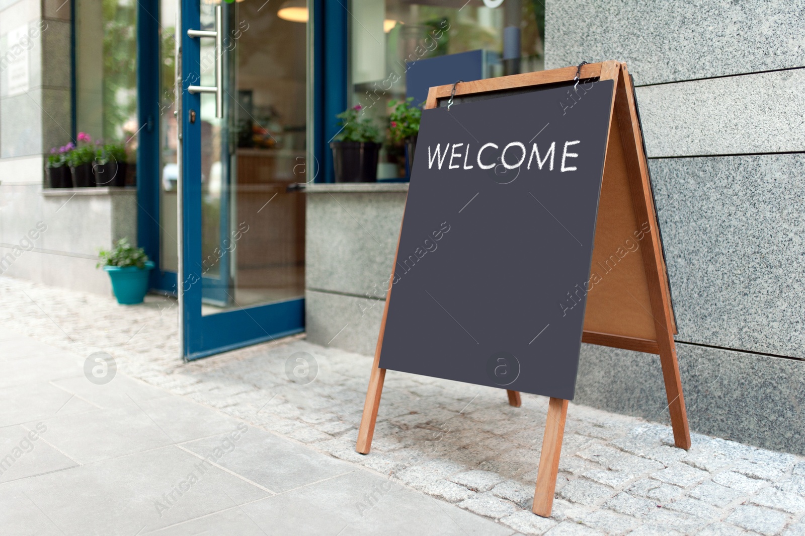 Image of Advertising board with word Welcome near restaurant entrance outdoors