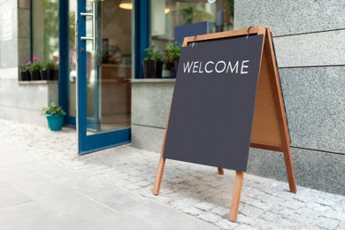 Image of Advertising board with word Welcome near restaurant entrance outdoors