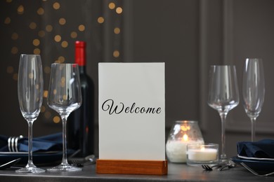 Image of Holder with word Welcome on table set for couple in restaurant