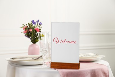 Image of Holder with word Welcome on table set for couple in restaurant