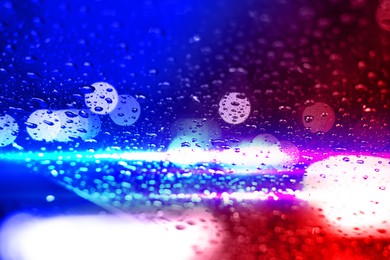 Image of Police red and blue lights, blurred view through wet glass