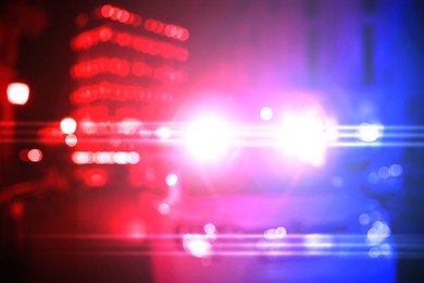 Image of Police car with red and blue lights in city at night, blurred view