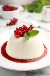 Photo of Delicious panna cotta with red currants, sauce and mint on white marble table, closeup