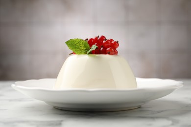 Photo of Delicious panna cotta with red currants, sauce and mint on white marble table against blurred background, closeup