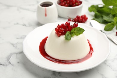 Photo of Delicious panna cotta with red currants, sauce and mint on white marble table, closeup