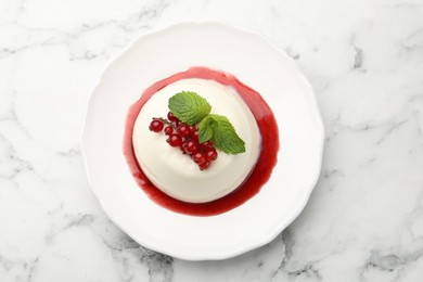 Photo of Delicious panna cotta with red currants, sauce and mint on white marble table, top view
