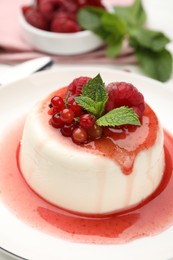 Photo of Delicious panna cotta with berries, sauce and mint on white table, closeup
