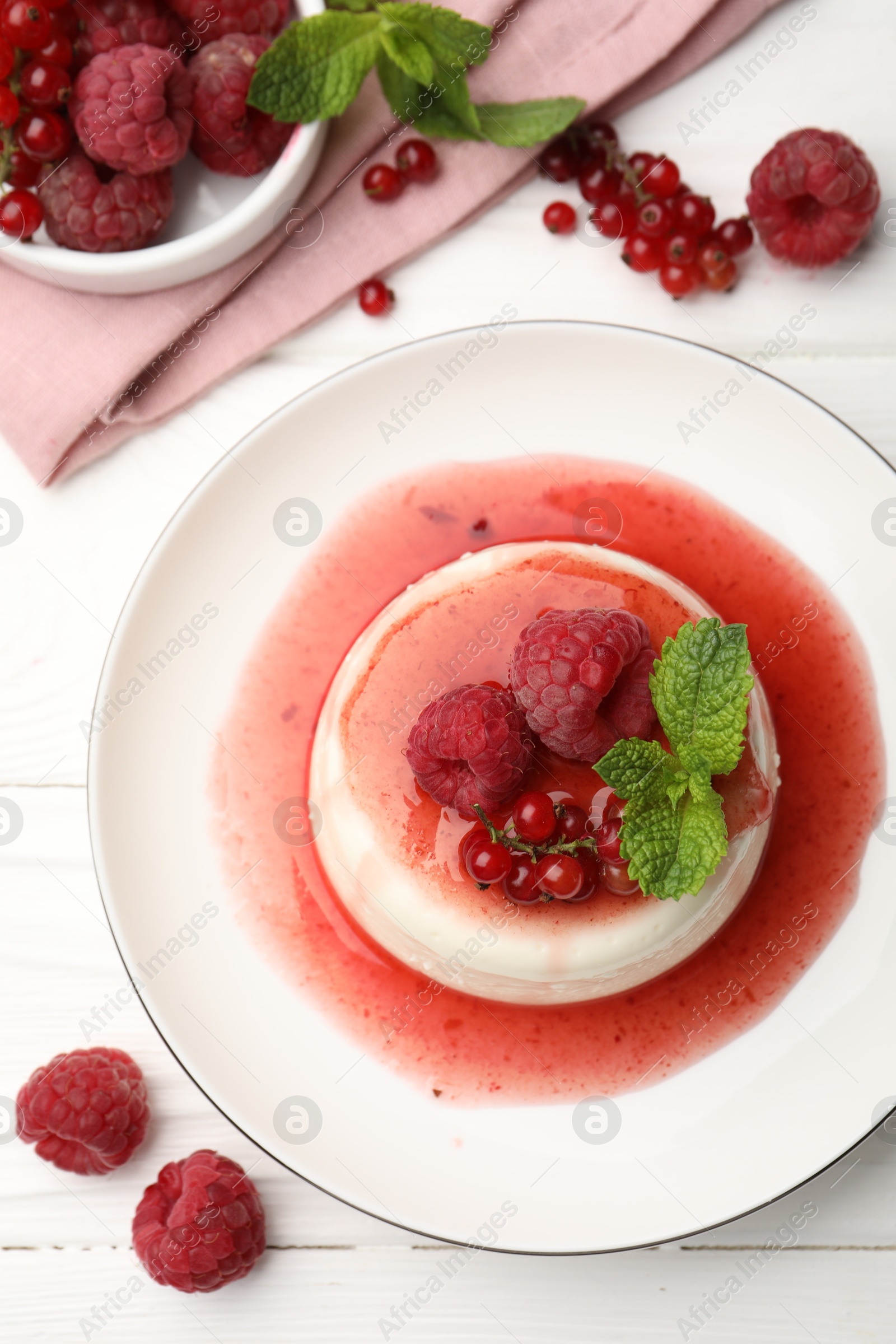 Photo of Delicious panna cotta with berries, sauce and mint on white wooden table, flat lay