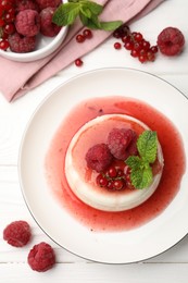 Photo of Delicious panna cotta with berries, sauce and mint on white wooden table, flat lay