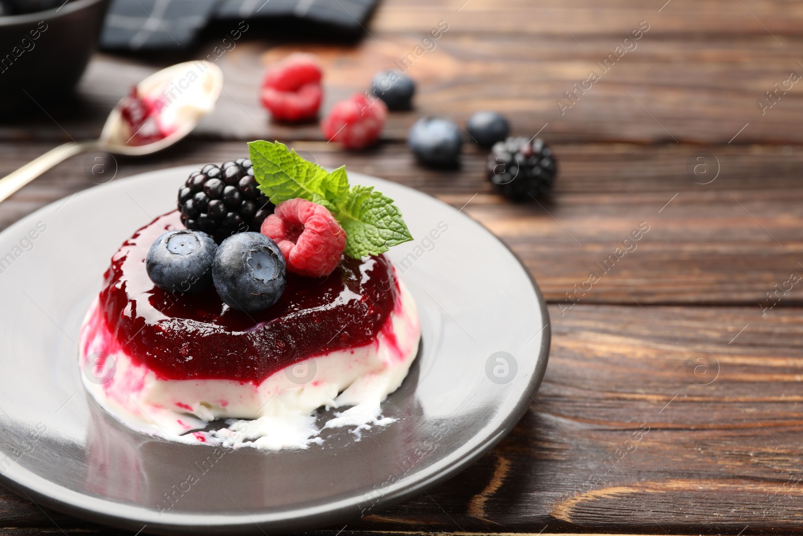 Delicious panna cotta with berries, jam and mint on wooden table, closeup Photo of Delicious panna cotta with berries, jam and mint on wooden table, closeup