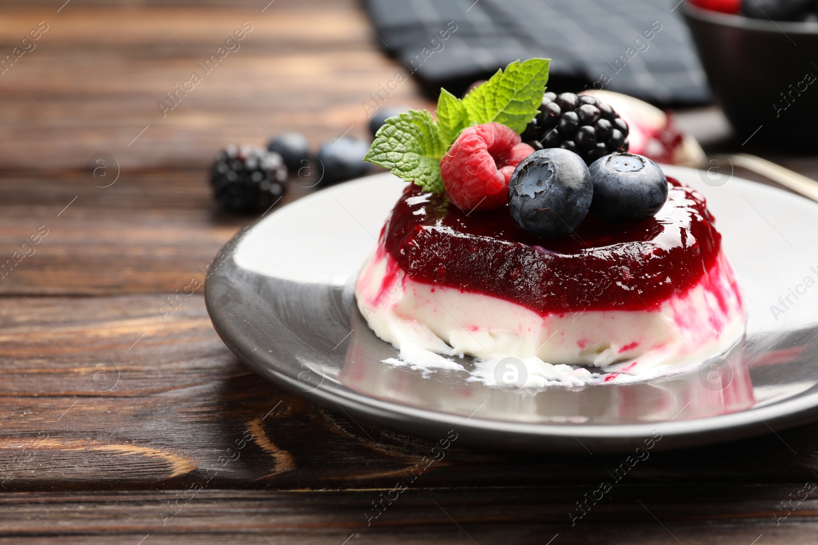 Delicious panna cotta with berries, jam and mint on wooden table, closeup Photo of Delicious panna cotta with berries, jam and mint on wooden table, closeup