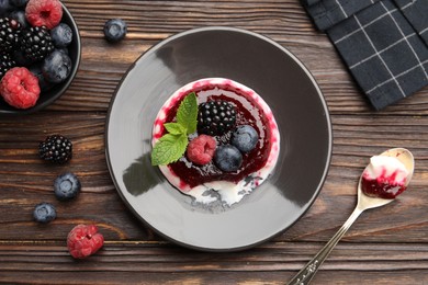 Photo of Delicious panna cotta with berries, jam and mint on wooden table, flat lay