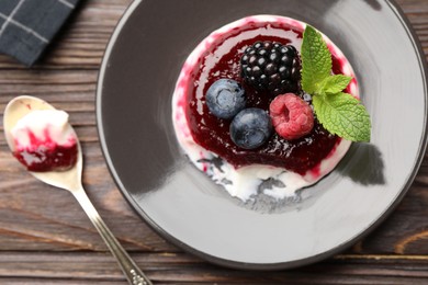 Photo of Delicious panna cotta with berries, jam and mint on wooden table, flat lay