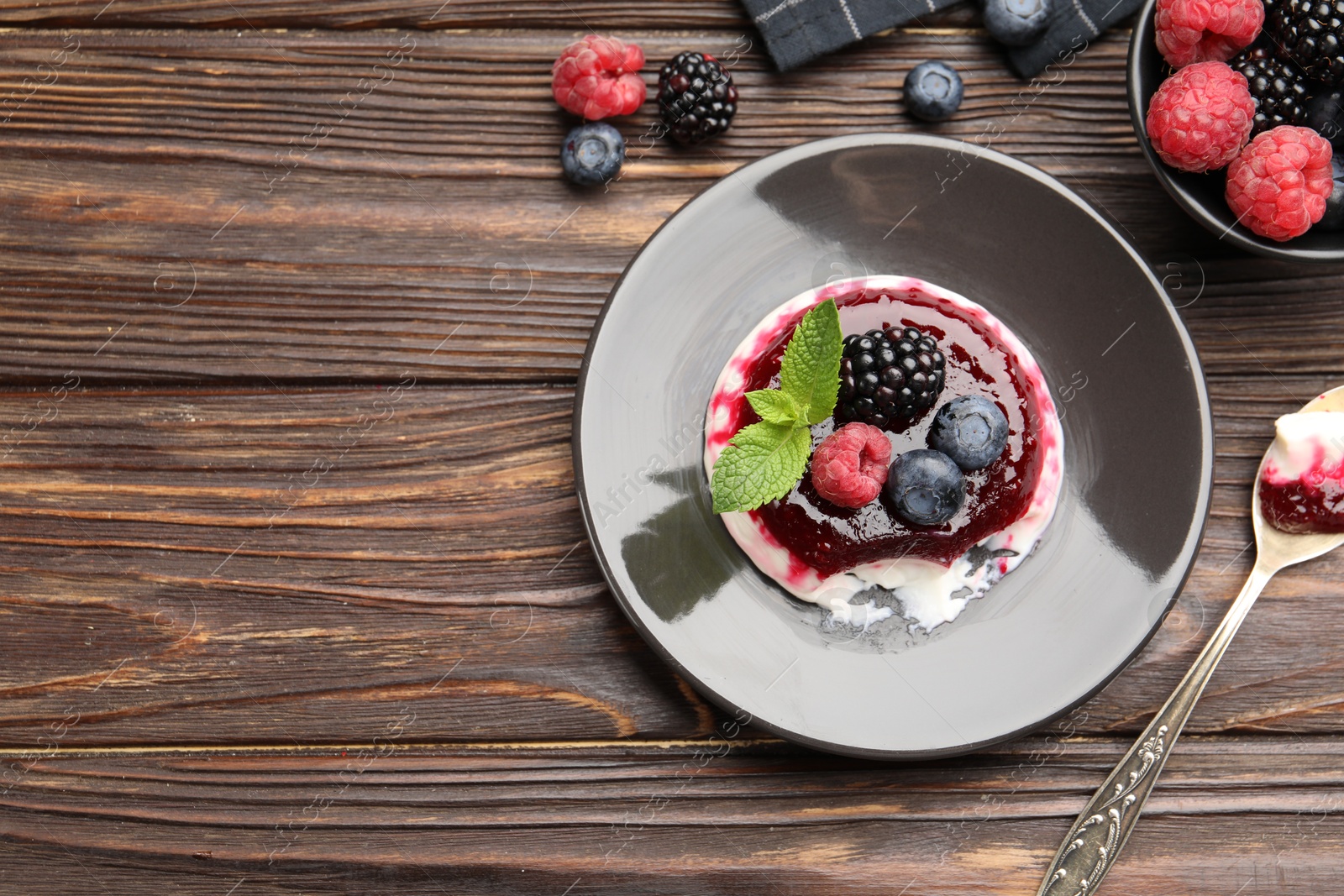 Delicious panna cotta with berries, jam and mint on wooden table, flat lay. Space for text Photo of Delicious panna cotta with berries, jam and mint on wooden table, flat lay. Space for text