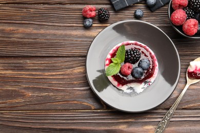 Photo of Delicious panna cotta with berries, jam and mint on wooden table, flat lay. Space for text