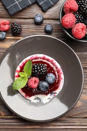 Photo of Delicious panna cotta with berries, jam and mint on wooden table, flat lay