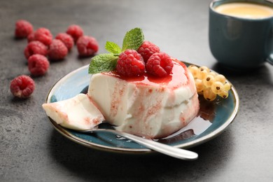 Photo of Delicious panna cotta with berries, sauce and mint on grey textured table, closeup