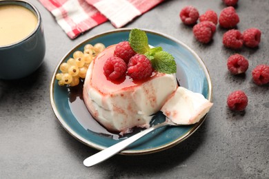 Photo of Delicious panna cotta with berries, sauce and mint on grey textured table, closeup