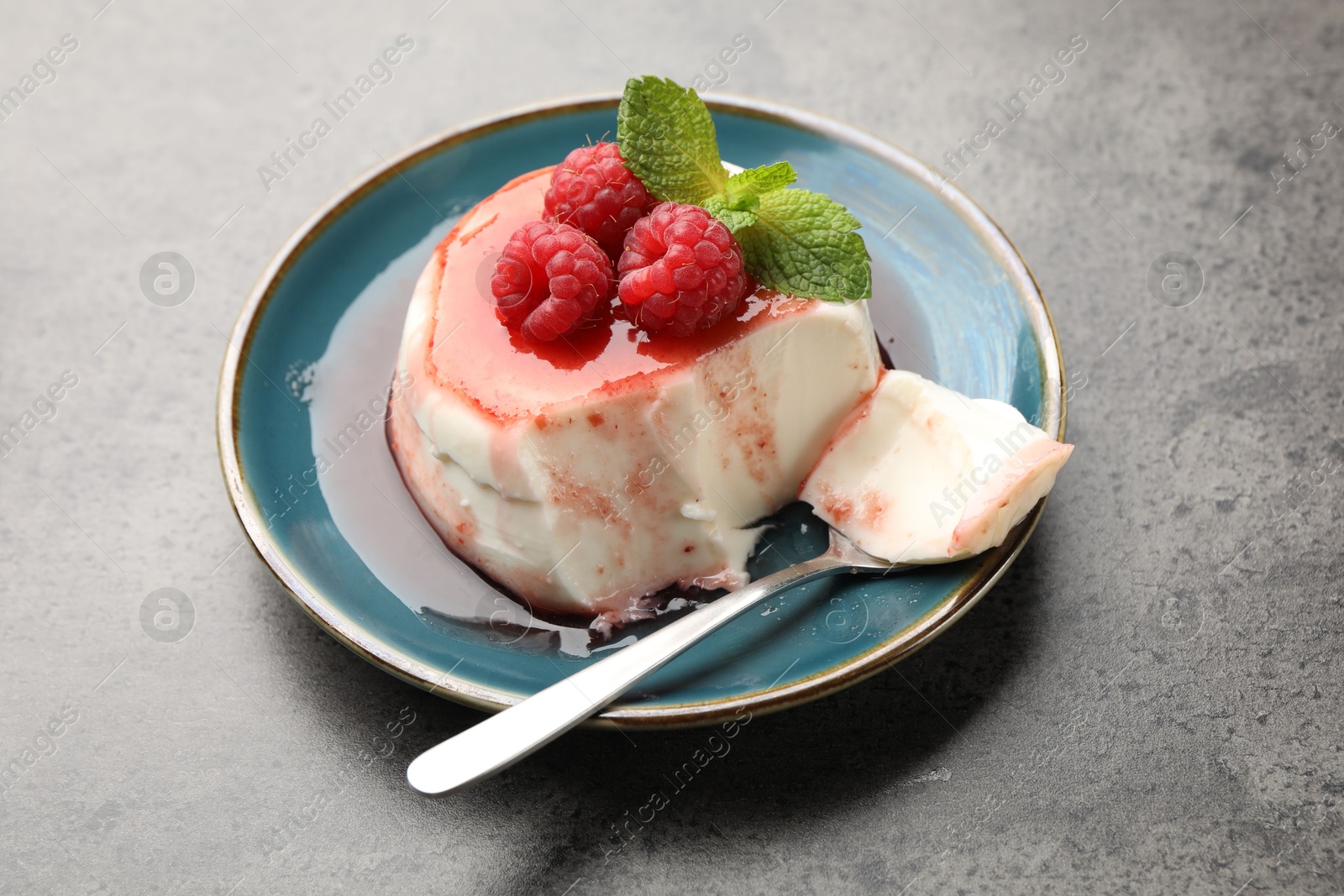 Delicious panna cotta with berries, sauce and mint on grey textured table, closeup Photo of Delicious panna cotta with berries, sauce and mint on grey textured table, closeup