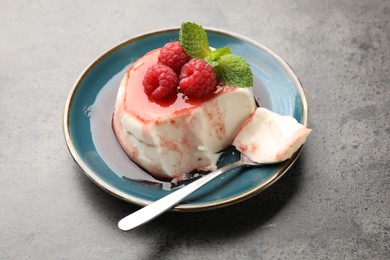 Photo of Delicious panna cotta with berries, sauce and mint on grey textured table, closeup
