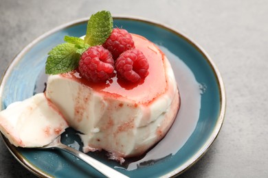 Photo of Delicious panna cotta with berries, sauce and mint on grey textured table, closeup