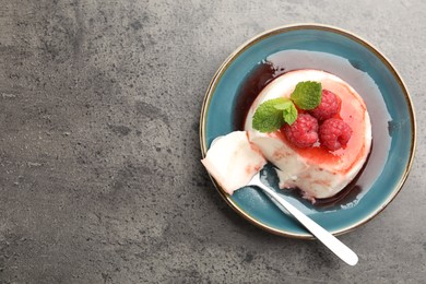 Photo of Delicious panna cotta with berries, sauce and mint on grey textured table, top view. Space for text