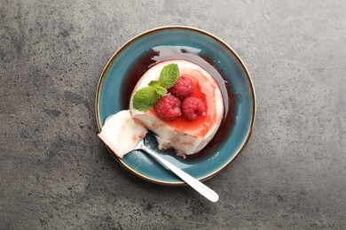Photo of Delicious panna cotta with berries, sauce and mint on grey textured table, top view