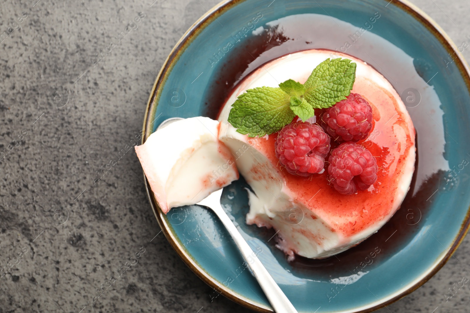 Delicious panna cotta with berries, sauce and mint on grey textured table, top view Photo of Delicious panna cotta with berries, sauce and mint on grey textured table, top view