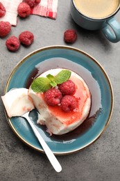 Photo of Delicious panna cotta with berries, sauce and mint on grey textured table, flat lay