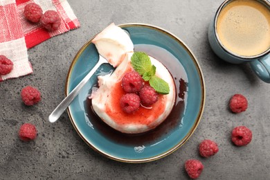 Photo of Delicious panna cotta with berries, sauce and mint on grey textured table, flat lay