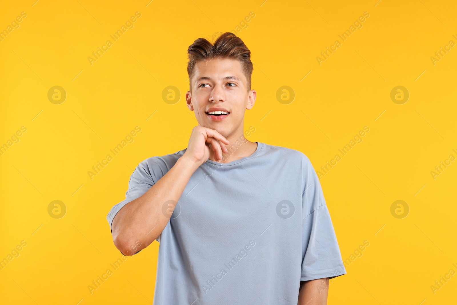 Dream come true. Positive young man thinking about something on yellow background Photo of Dream come true. Positive young man thinking about something on yellow background